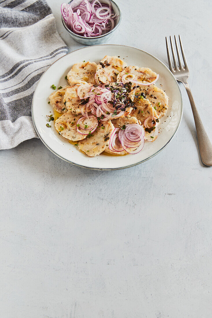 Dumpling carpaccio with parsley and red onions