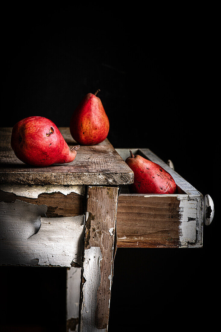 Unvollkommene rote Birnen auf altem Tisch