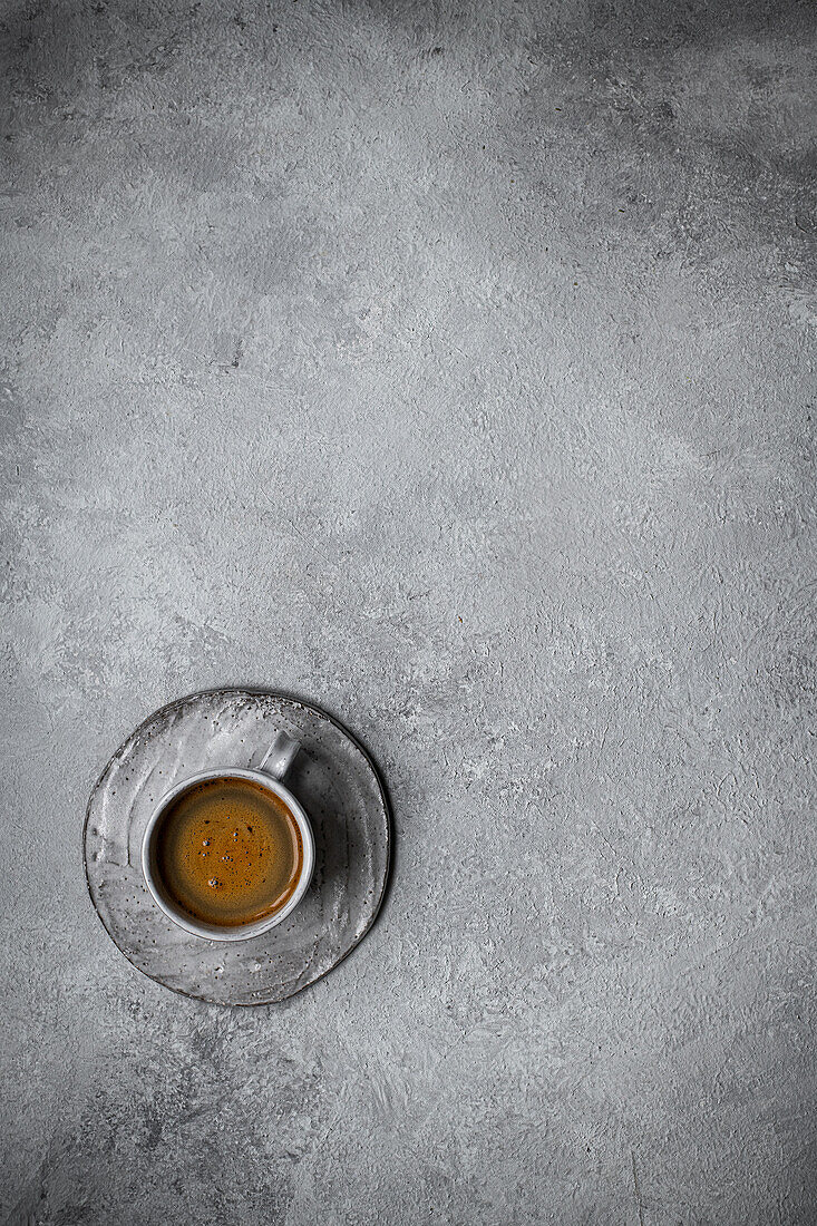 Schwarzer Kaffee in einer Tasse mit strukturiertem, grauen Hintergrund