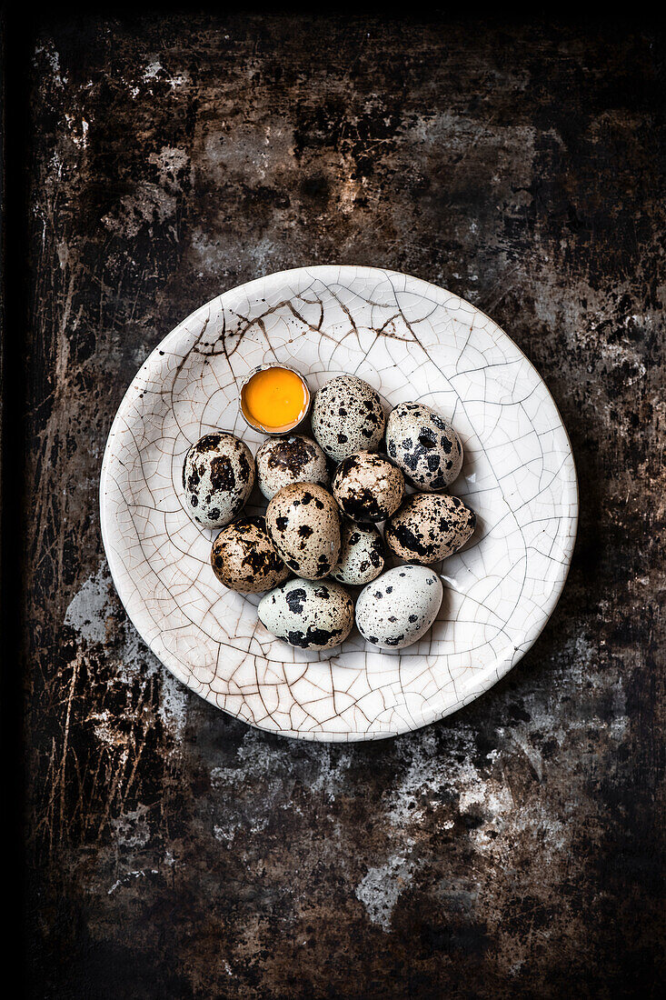 Quail eggs in a bowl, one cracked open