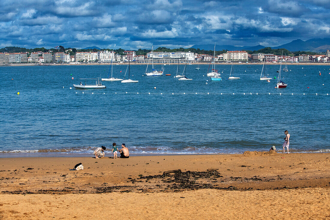 Ciboure beach with few tourist and Saint jean de Luz bay with luxurious boats on background Basque country. France