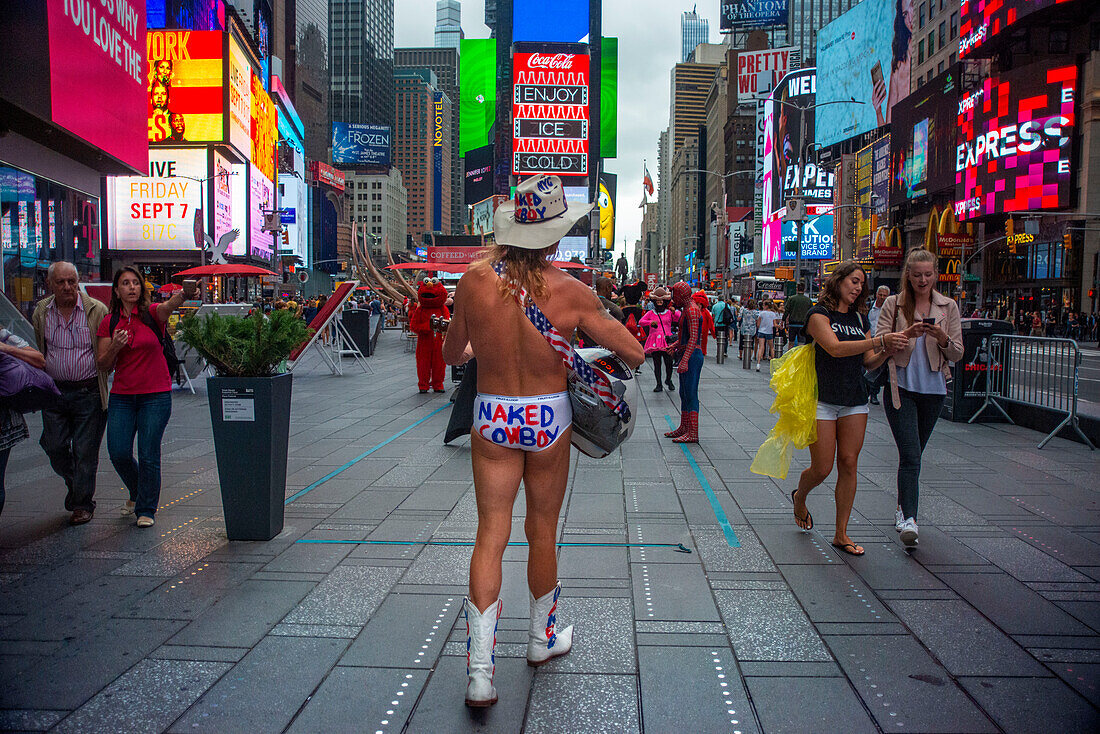 Robert Burck, besser bekannt als der Naked Cowboy, tritt in der Abenddämmerung auf dem Times Square auf. Manhattan, New York City, Vereinigte Staaten von Amerika