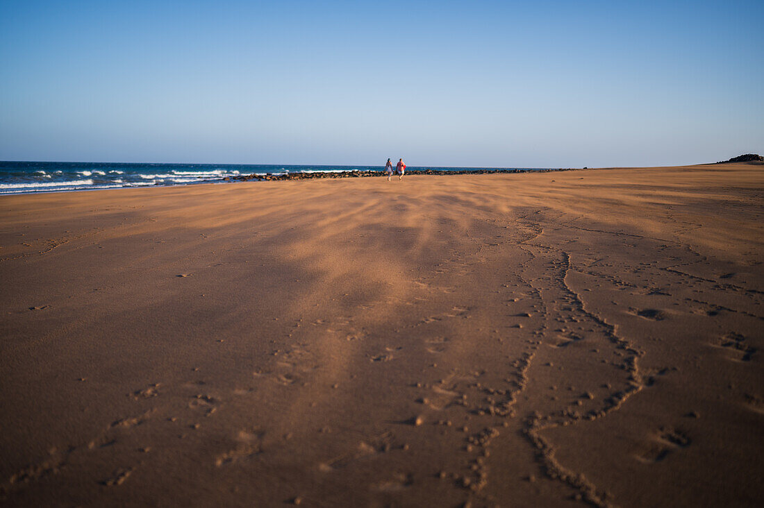 Couple walks on the beach as a strong wind blows sand in Lanzarote, Canary Islands, Spain