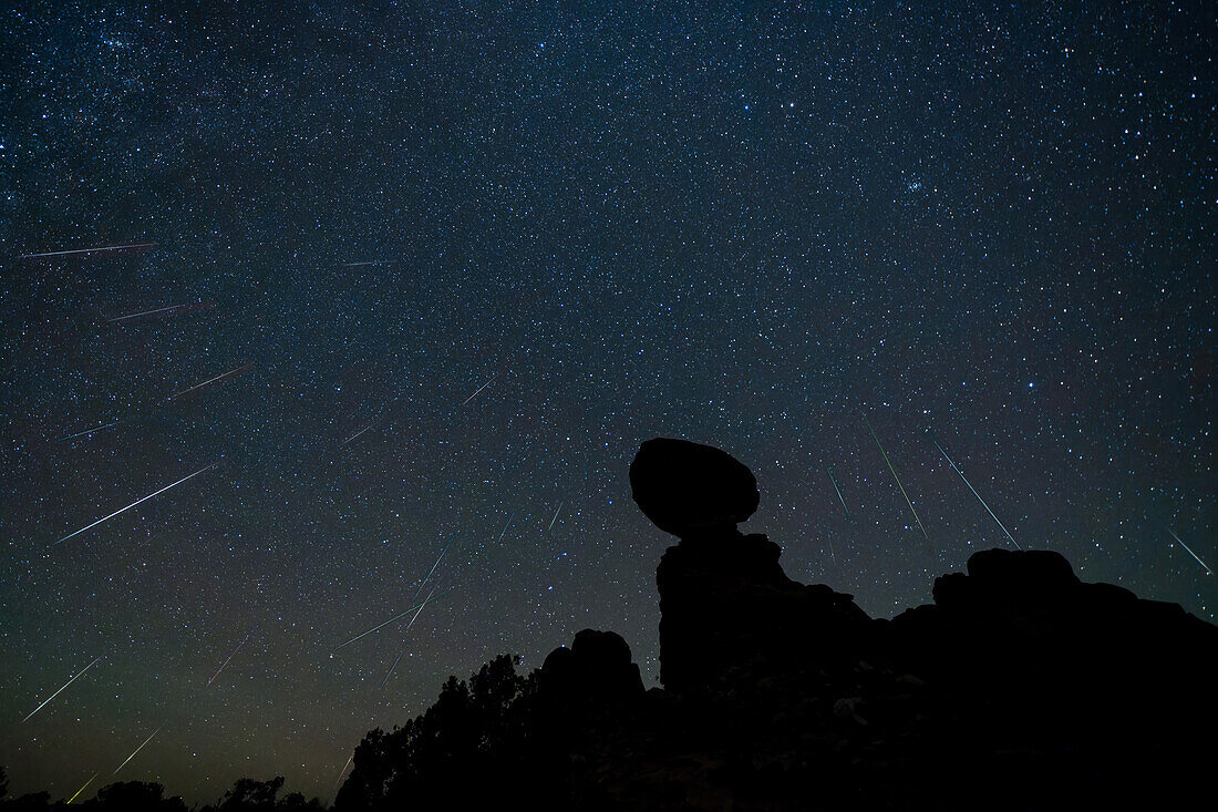 Geminiden-Meteoritenschauer über dem Balanced Rock im Arches National Park in Utah. Kompositbild zeigt 24 Meteoriten über einen Zeitraum von 2 Stunden