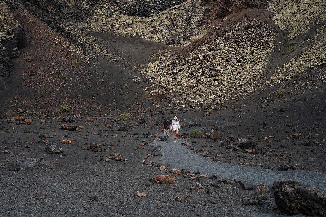 Volcan del Cuervo (Krähenvulkan) ein Krater, der über einen Rundweg in einer kargen, felsigen Landschaft erkundet wird