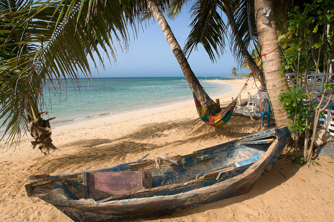 Fisher boat in Las Terrenas beach, Samana, Dominican Republic, Carribean, America. Tropical Caribbean beach with coconut palm trees.