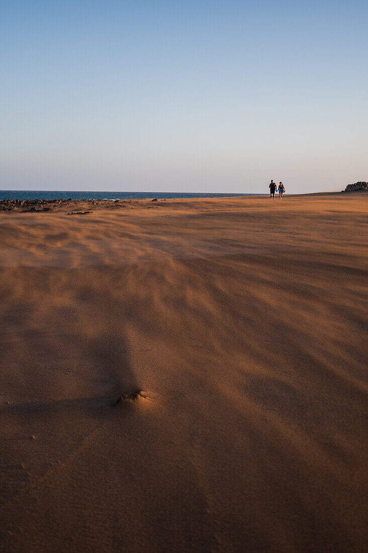 Couple walks on the beach as a strong wind blows sand in Lanzarote, Canary Islands, Spain