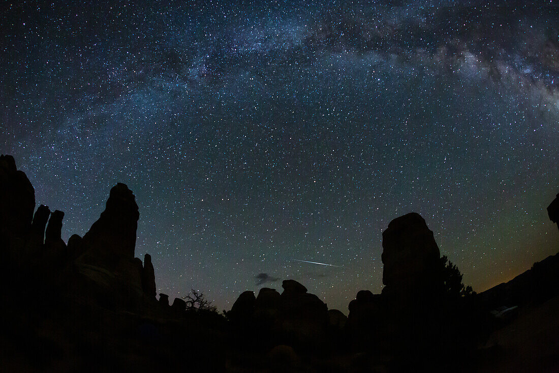 Eine Sternschnuppe und die Milchstraße über Sandsteintürmen im Needles District des Canyonlands National Park in Utah
