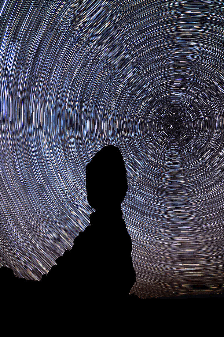 Sternspuren, die den Nordstern über dem Balanced Rock im Arches National Park im Winter in Utah umkreisen. Kompositbild aus 180 20-Sekunden-Belichtungen über eine Stunde