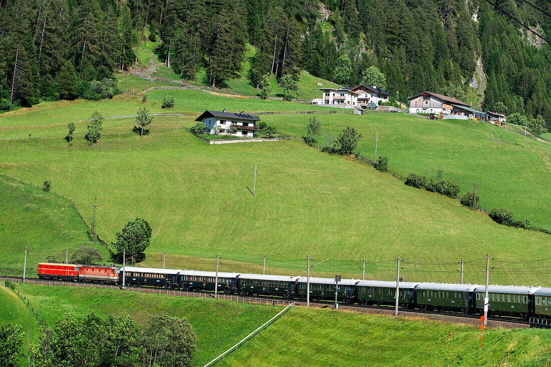 Train running along Renon plateau with Dolomites scenery. Belmond Venice Simplon Orient Express luxury train.