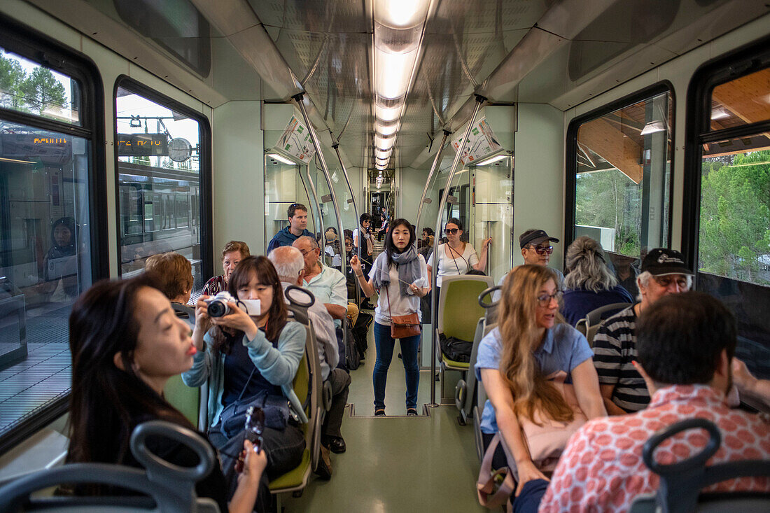 Asian tourists inside the cremallera Rack railway train climbing up Montserrat mountain, Monistrol de Montserrat, Barcelona, Spain.