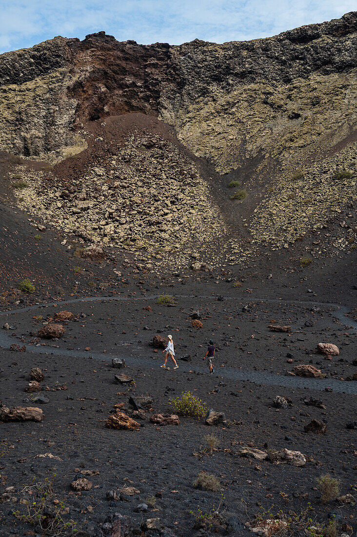 Volcan del Cuervo (Krähenvulkan), ein Krater, der über einen Rundweg in einer kargen, felsigen Landschaft erkundet wird