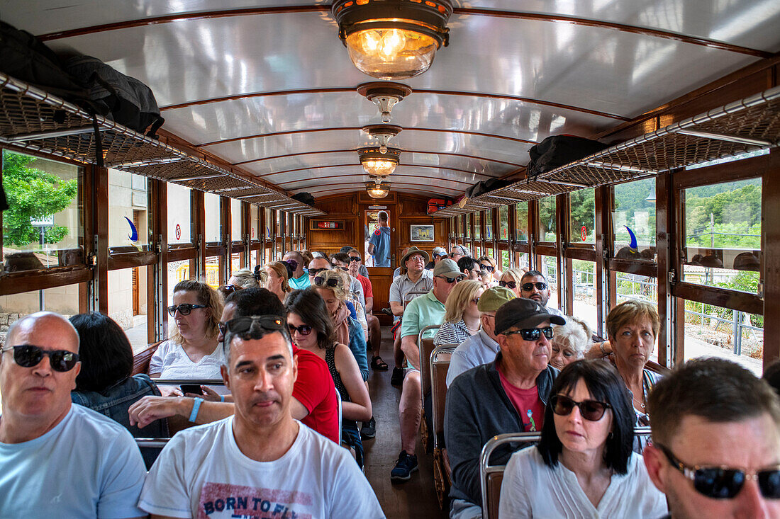 Touristen im Inneren des Tren de Soller, eines historischen Zuges, der Palma de Mallorca mit Soller verbindet, Mallorca, Balearen, Spanien, Mittelmeer, Europa