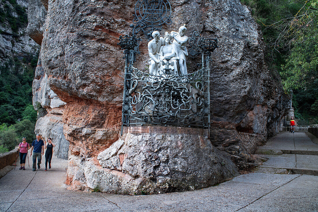 Weiße Christusstatue mit Dornenkrone, römischer Soldat, eine weitere Figur und ein Eisenwerk mit Kreuz auf dem Weg zur Kapelle Santa Cova auf dem Berg Montserrat in Monistrol de Montserrat, Barcelona, Katalonien, Spanien