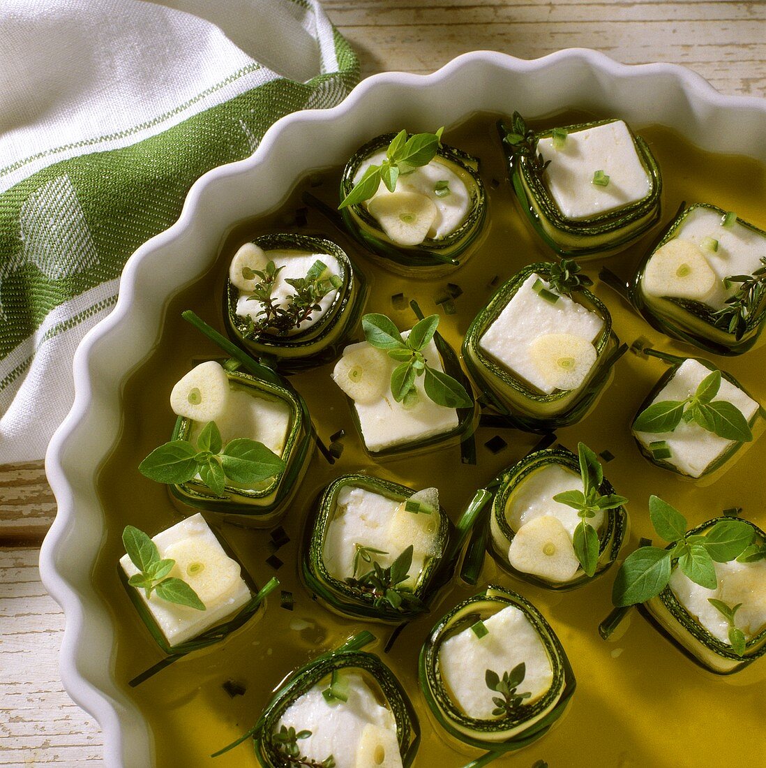 Sheep's cheese & courgette snacks in a dish with olive oil