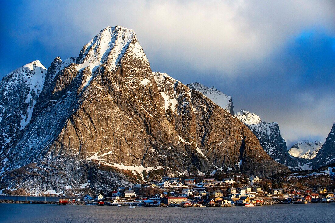 Blick über den natürlichen Fischerhafen auf die hoch aufragenden Berge über Reine, Moskenes, Insel Moskenesøya, Lofoten, Norwegen