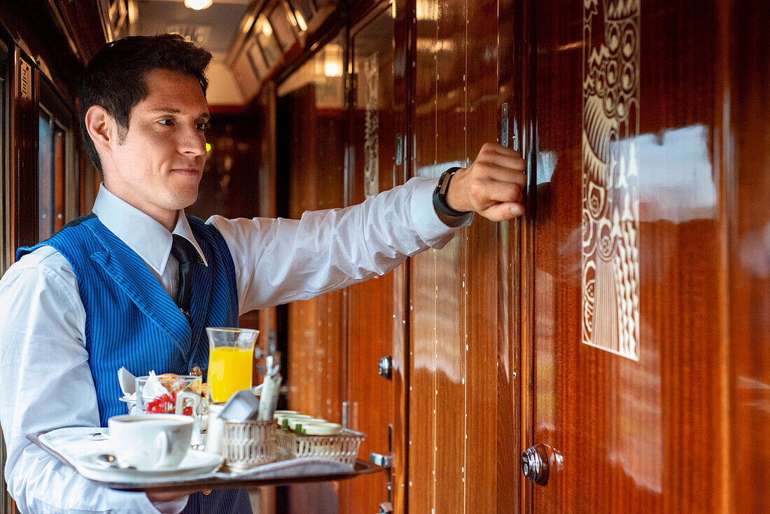 Ein Kellner serviert das Frühstück in einem der Einzelabteile des Luxuszuges Belmond Venice Simplon Orient Express in der Nähe von Paris