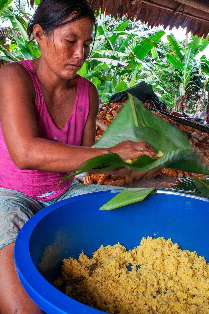 Frau bereitet Juanes hausgemachte Mais- und Hühnertamales nach traditioneller Methode in Timicuro I, Iqutios peruanischer Amazonas, Loreto, Peru