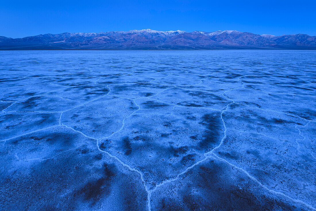 Salt formation polygons at Badwater Basin and the Panamint Mountains at dawn in Death Valley National Park, California.