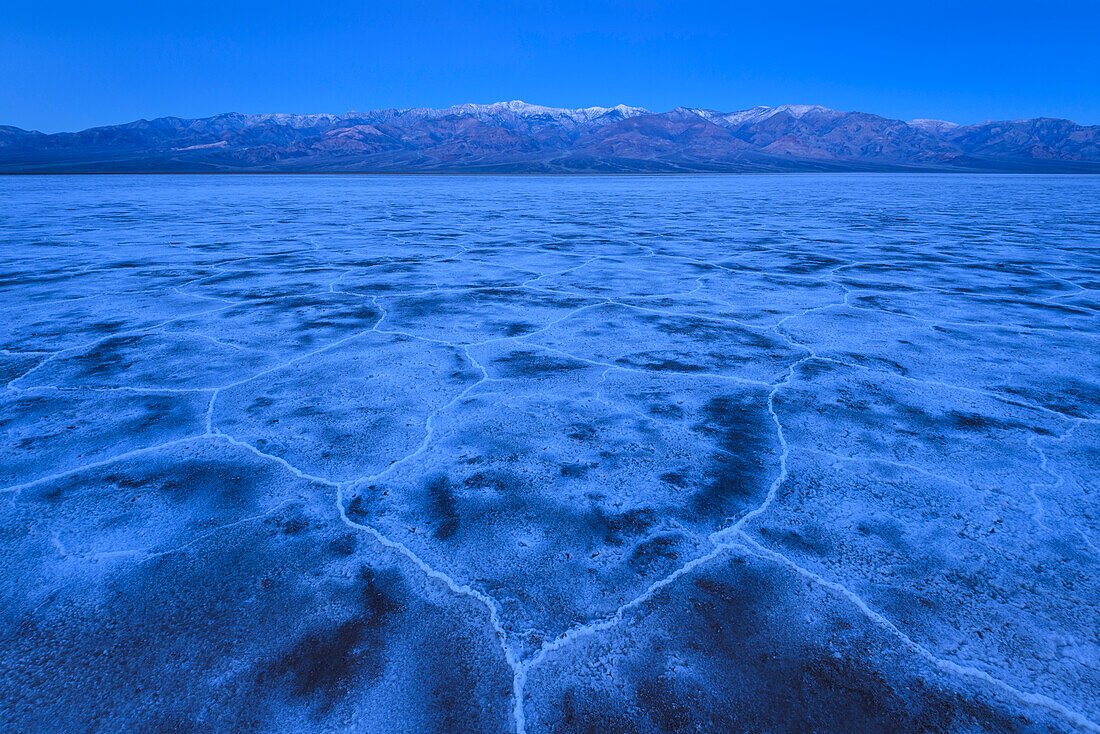 Salzformationen im Badwater Basin und in den Panamint Mountains bei Sonnenaufgang im Death Valley National Park, Kalifornien