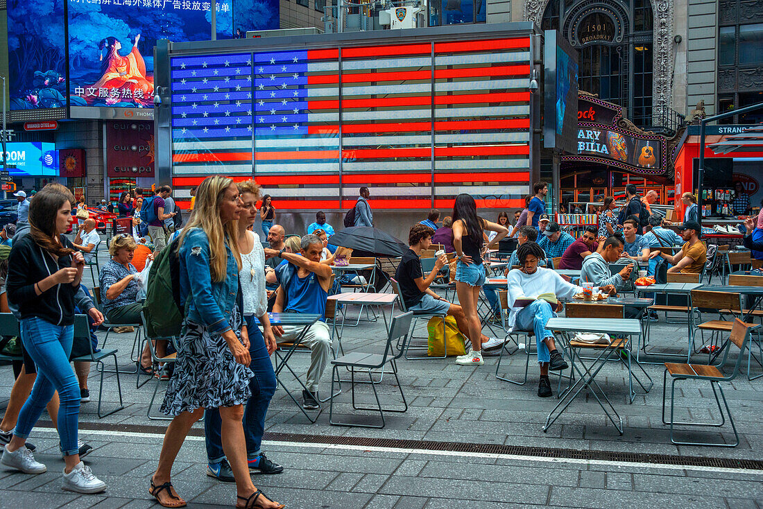Große amerikanische Flagge am Times Square, New York City bei Nacht. Menschenmenge am Times Square an einem Herbstabend, Midtown Manhattan, NY, USA