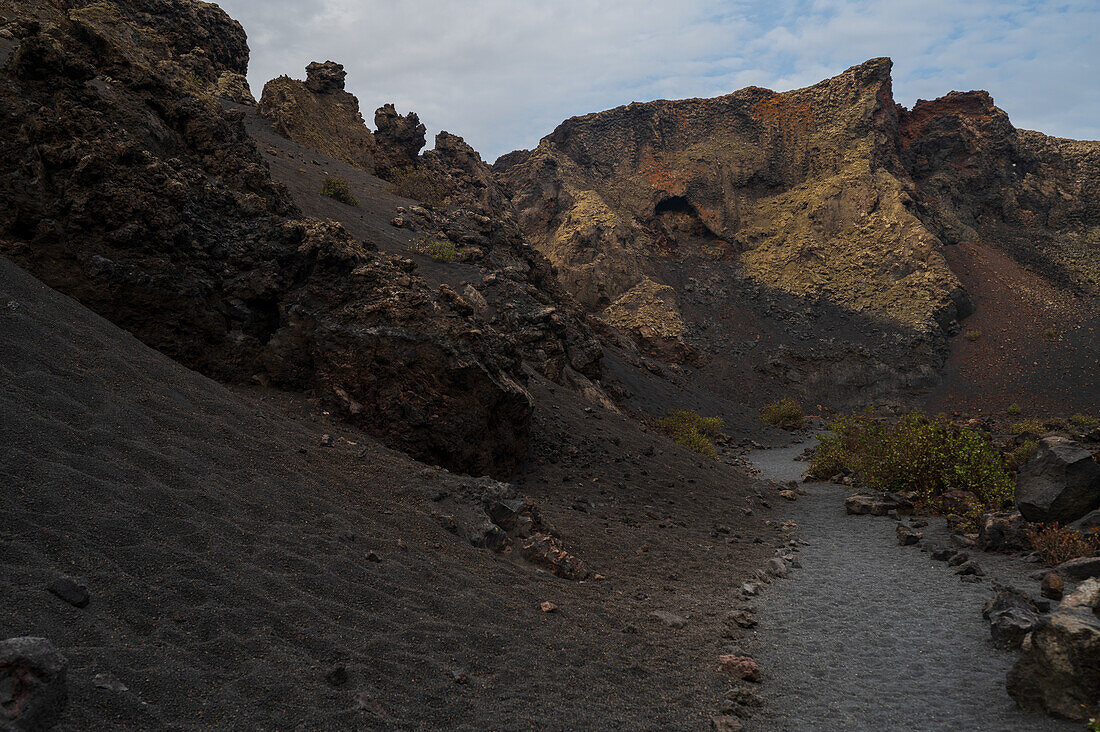 Volcan del Cuervo (Krähenvulkan), ein Krater, der auf einem Rundweg in einer kargen, felsdurchsetzten Landschaft erkundet wird