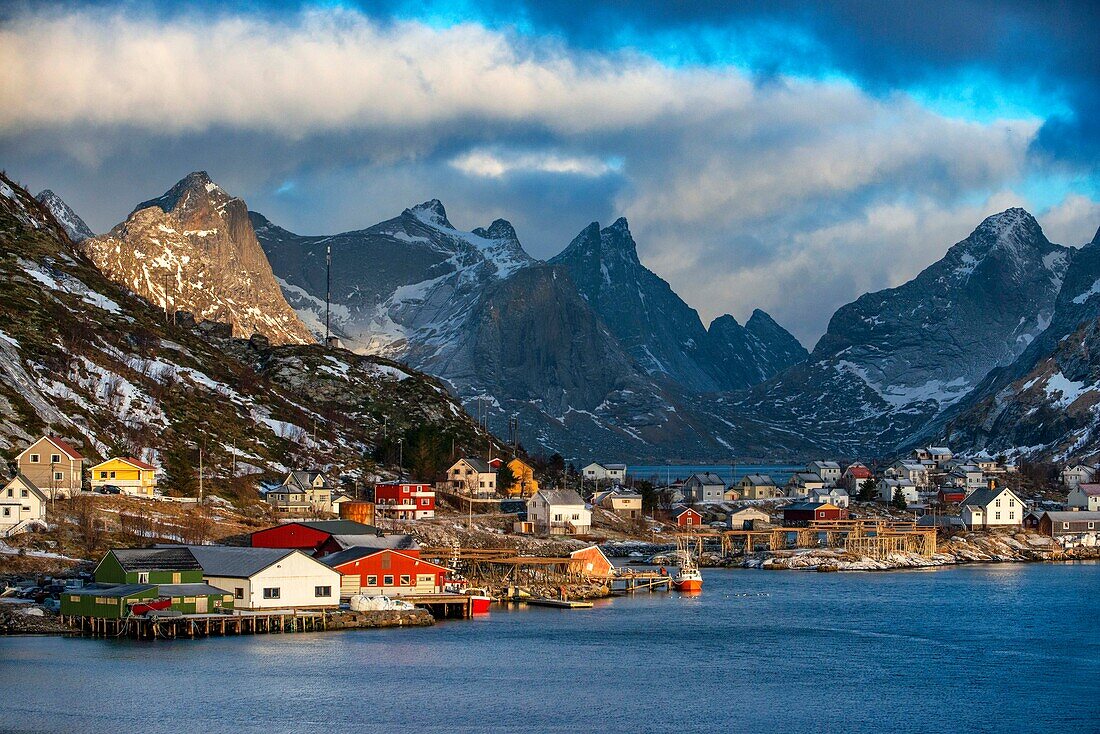 Blick über den natürlichen Fischereihafen auf die hoch aufragenden Berge über Reine, Moskenes, Insel Moskenesøya, Lofoten, Norwegen