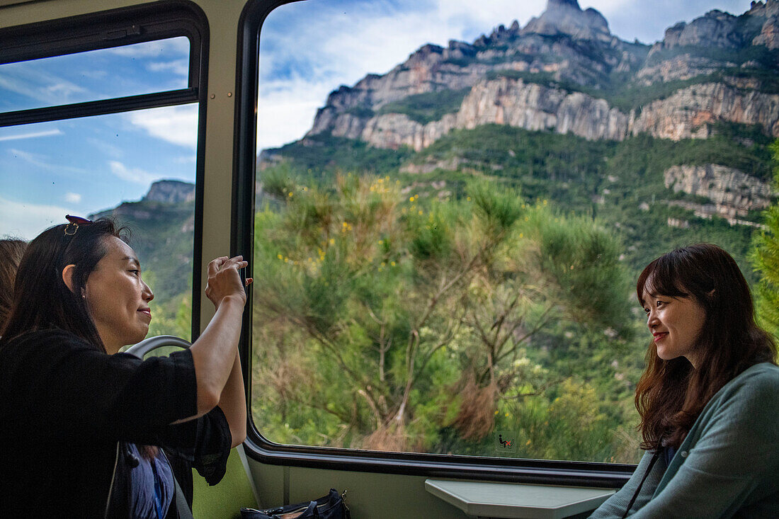 Asian tourists inside the cremallera Rack railway train climbing up Montserrat mountain, Monistrol de Montserrat, Barcelona, Spain.