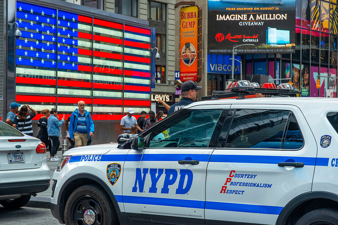 Big american flag and New York City Police Department Emergency Service Unit officer on Wall Street in New York City New York USA