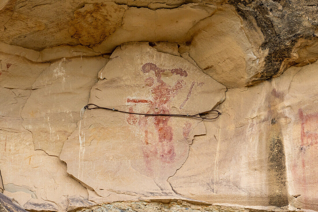 Prähispanische Piktogramme an der Kokopelli Interpretive Site im Canyon Pintado National Historic District in Colorado. Man beachte das Stabilisierungsseil, das die Felsplatte an ihrem Platz hält.