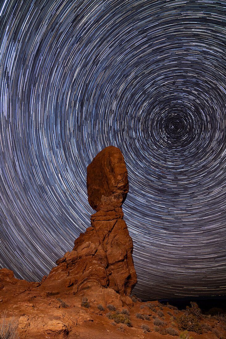 Sternspuren, die den Nordstern über dem Balanced Rock im Arches National Park im Winter in Utah umkreisen. Zusammengesetztes Bild aus 180 20-Sekunden-Belichtungen über eine Stunde
