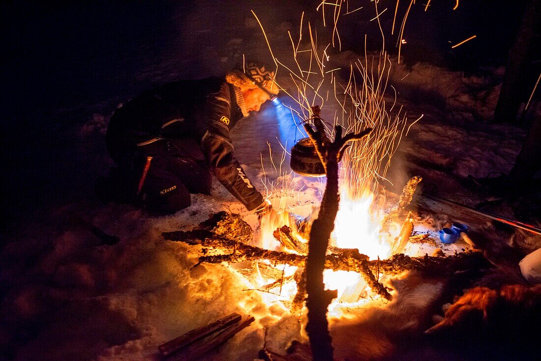 Teestunde im Schnee. Schneeschuhwanderung bei Nacht, um die Nordlichter in Mosjoen, Norwegen, zu sehen. Kochtopf auf offenem Feuer