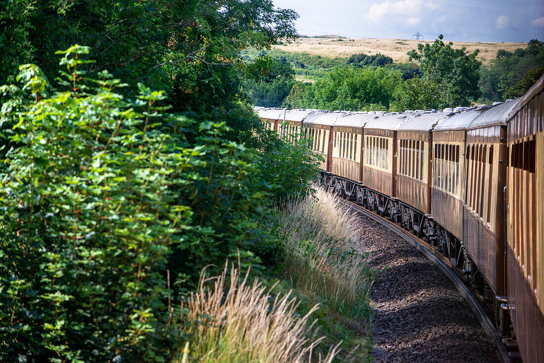 Green landscape in the Belmond British Pullman luxury train running beetween Folkestone and London Victoria train station.