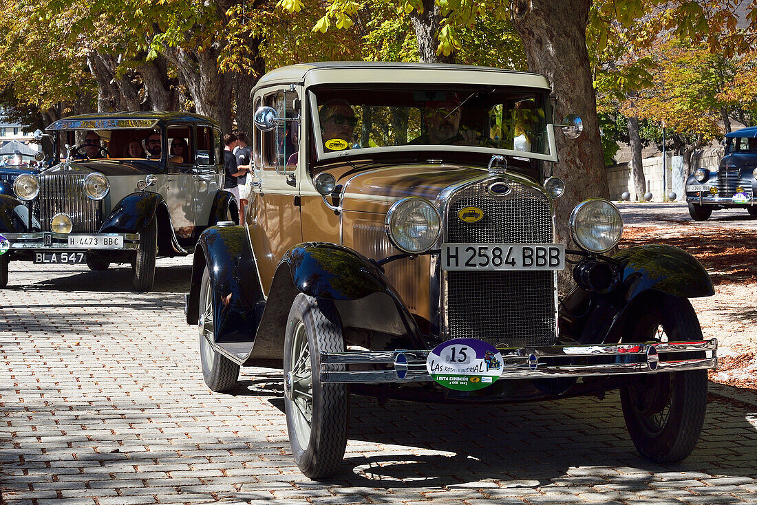 Ein Ford und ein Rolls Royce Oldtimer auf der Straße bei einem Autofestival in San Lorenzo de El Escorial, Madrid