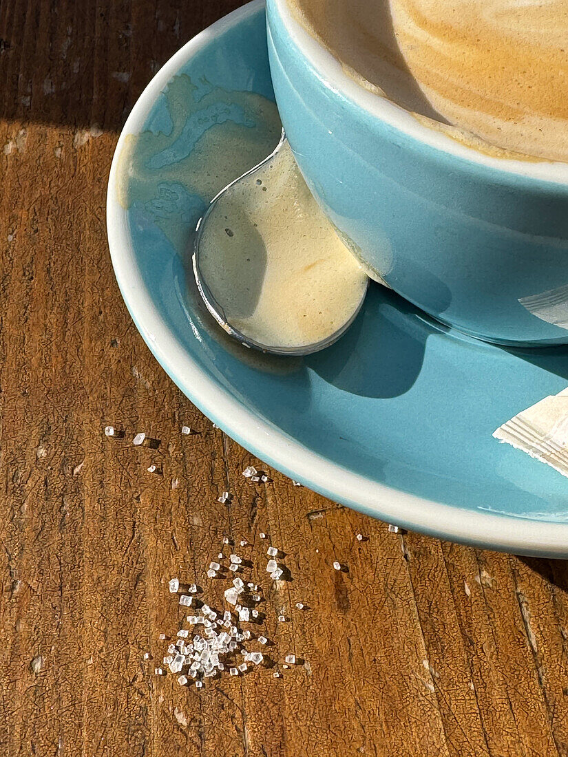 Sugar spilled next to coffee on table