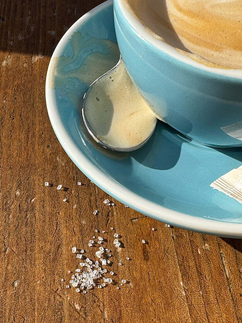 Verschütteter Zucker neben Kaffee auf dem Tisch