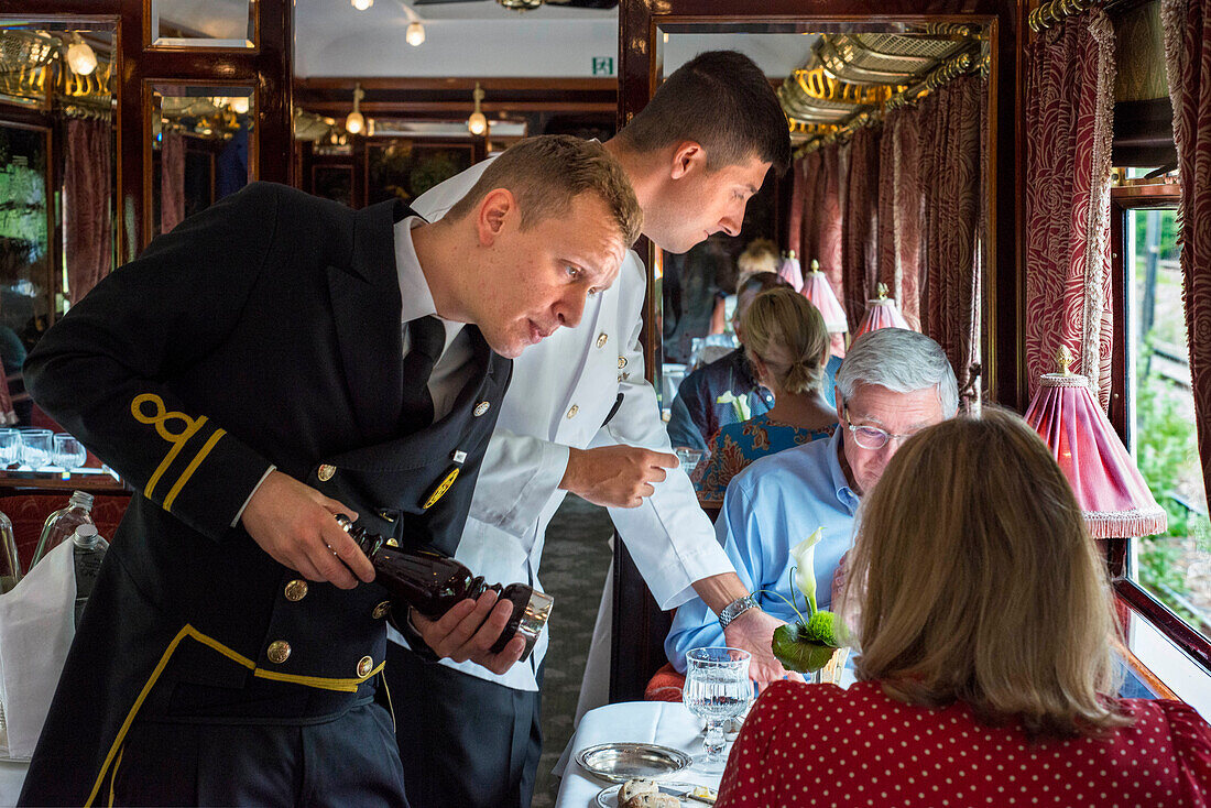 Ein Kellner serviert das Mittagessen im Art-Deco-Restaurantwagen des Luxuszuges Belmond Venice Simplon Orient Express. Lachskraut und Kartoffeln