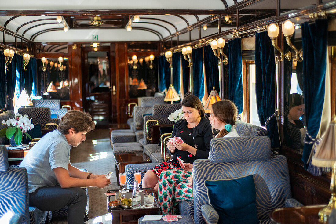 Customers in the art deco bar lounge wagon of the train Belmond Venice Simplon Orient Express luxury train.