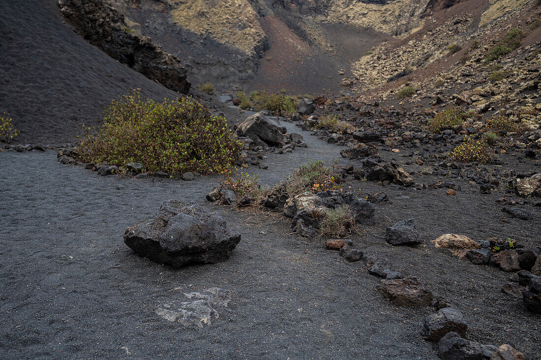 Volcan del Cuervo (Krähenvulkan) ein Krater, der auf einem Rundweg in einer kargen, felsigen Landschaft erkundet wird