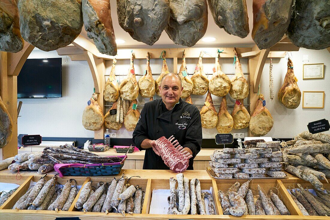 France, Hautes Pyrenees, Beaucens, portrait of Pierre Sajous, artisan pork butcher specializing in Black Pig of Bigorre and game, holding in his hands a piece of black pork chop from Bigorre