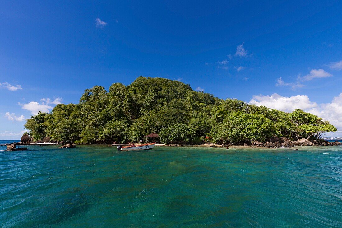 Martinique, Karibisches Meer, Trois Ilets, Woodpecker Island ist eine unbewohnte Insel, die zum Conservatoire du Littoral gehört, im Vordergrund die Reste eines Pontons, ein kleines Motorboot ankert vor dem kleinen Sandstrand