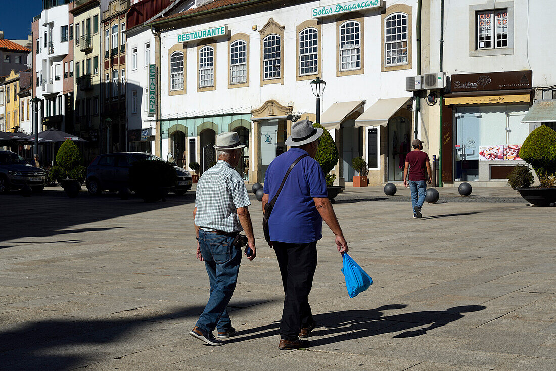 Two men walking near Praça da Sé in Bragança, Portugal.