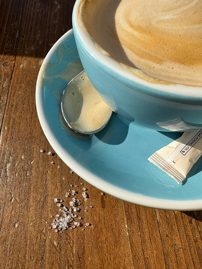 Sugar spilled next to coffee on table