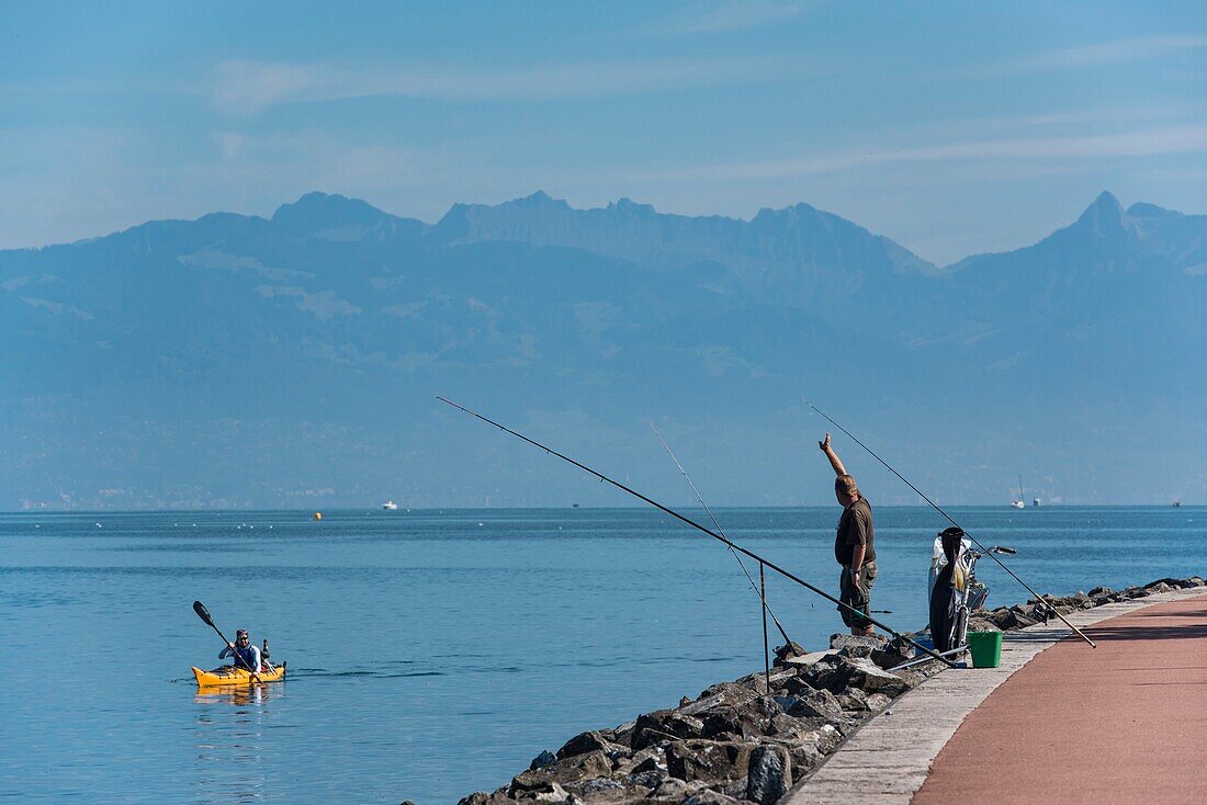 Frankreich, Hochsavoyen, Evian les Bains, Fischer und Kanu nebeneinander am Ufer des Leman-Sees