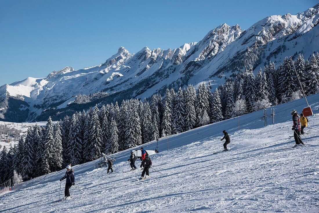 France, Haute Savoie, La Clusaz, skiers on the tracks of Crêt du Merle and the peaks of the Aravis massif