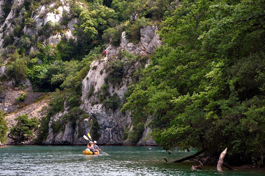 Frankreich, Alpes de Haute Provence, Parc Naturel Regional du Verdon, Kajak in den Basses Gorges du Verdon flussabwärts des Sees St. Croix und der in den Felsen gehauene Kanalwächterweg im Hintergrund