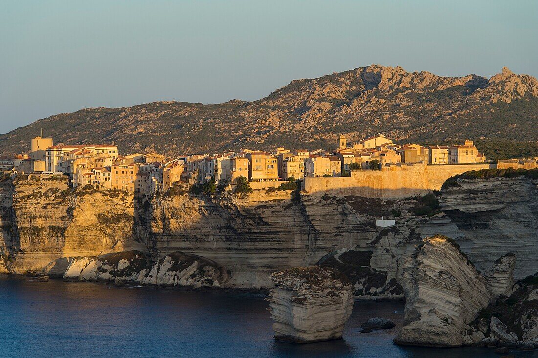 Frankreich, Corse du Sud, Bonifacio, die Zitadelle auf der Klippe mit Blick auf den Sonnenaufgang, der Sandkornfelsen und die Einsiedelei der Trinite auf dem Berg am Horizont