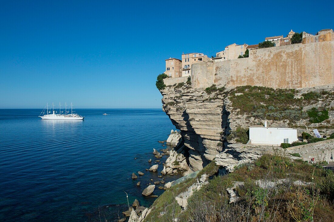 France, Corse du Sud, Bonifacio, the upper town located in the citadel is built on limestone cliffs overlooking the sea where is anchored the sailboat 4 mats of the Mediterranean club in the foreground chapel Saint Roch