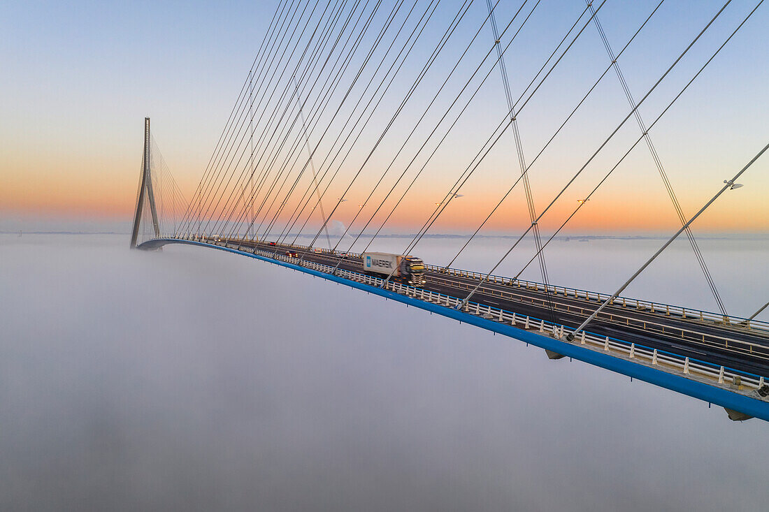 France, between Calvados and Seine Maritime, the Pont de Normandie (Normandy Bridge) emerges from the morning mist of autumn and spans the Seine to connect the towns of Honfleur and Le Havre (aerial view)