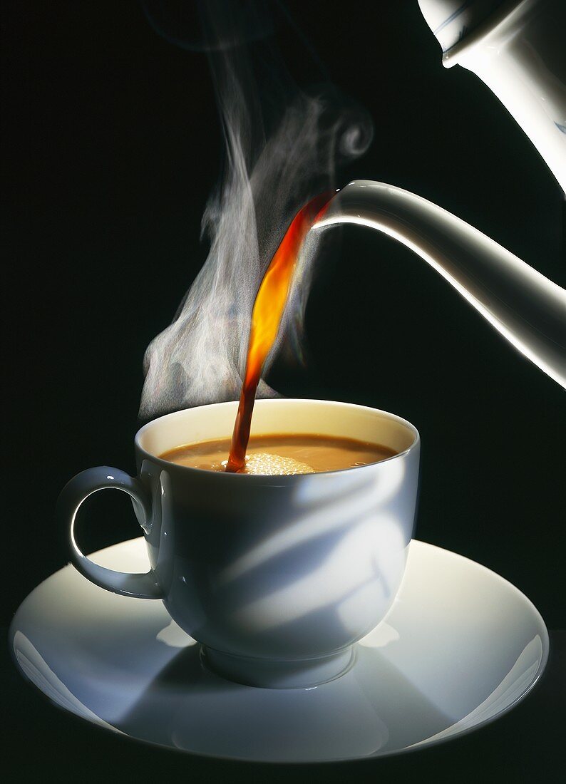 Kaffee wird in Tasse gegossen, schwarzer Hintergrund